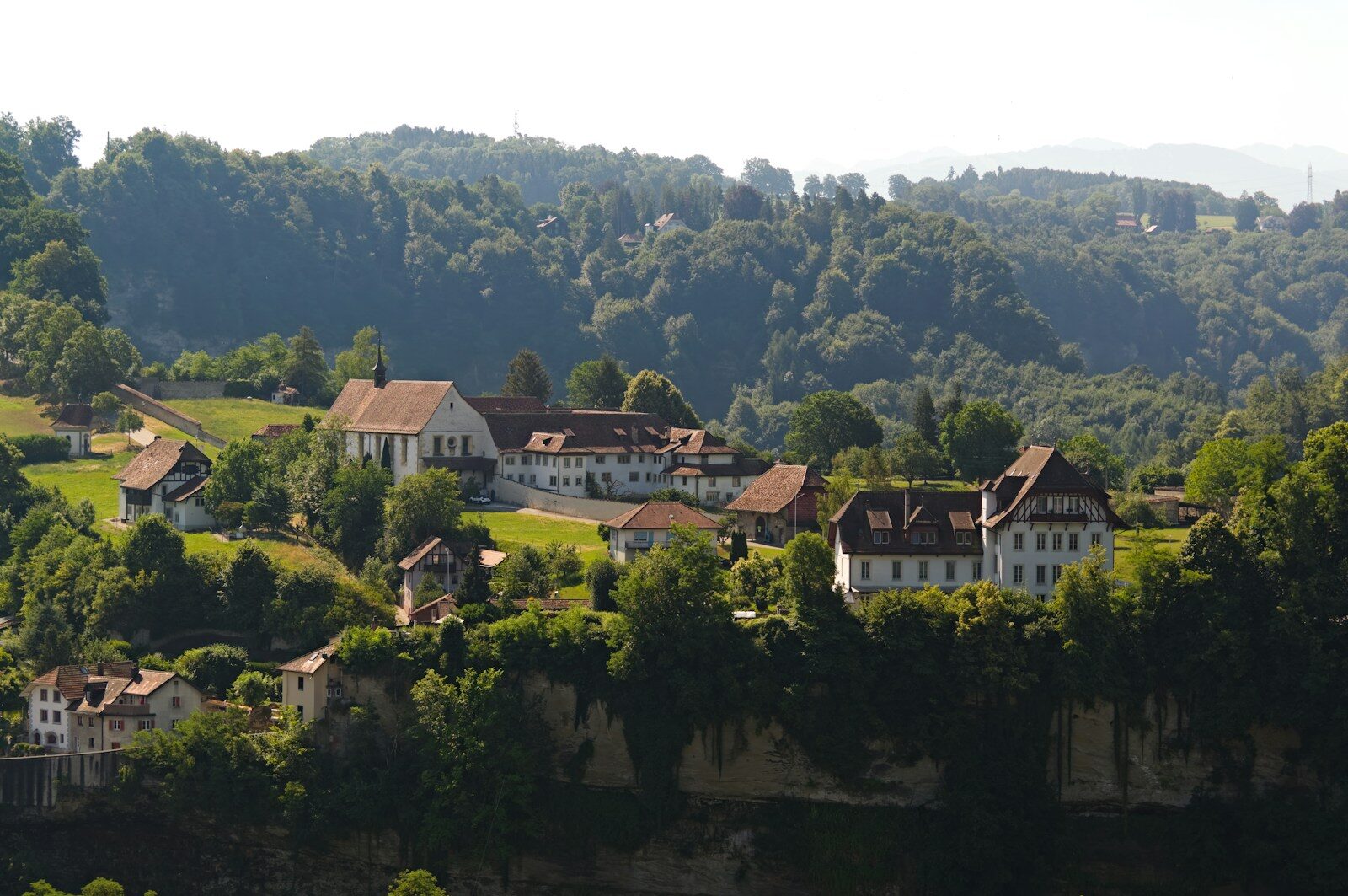 European village buildings on a cliff overlooking a forested valley